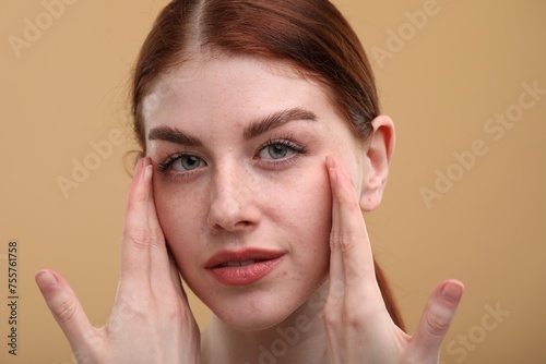 Portrait of beautiful woman with freckles on beige background, closeup