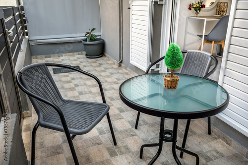 Small balcony arrangement with table and chairs, creating inviting outdoor space. Featuring modern design in grey and white colors. deal for illustrating outdoor living concepts and urban lifestyle. 