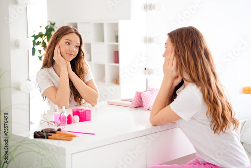 Photo of peaceful cute female person sit chair hand touch cheek look mirror reflection modern bedroom house inside
