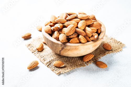 Almond nuts in wooden bowl at white background. Close up. photo