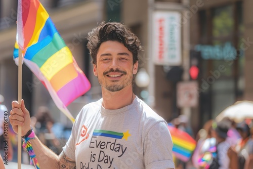 a man holding a pride flag wearing a t shirt with the word "Everyday is Pride Day" on it 