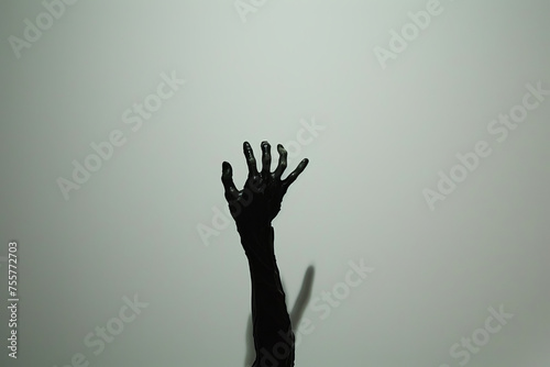 The silhouette cast by a zombie's hand emerges starkly against a plain white backdrop. photo