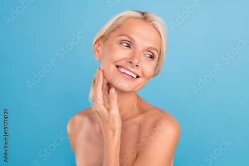 Photo of dreamy cute elderly lady naked shoulders enjoying soft skin arms touch cheekbones isolated blue color background