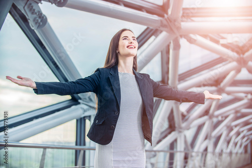 A beautiful businessman woman spreading her arms as a symbol of freedom against the background of a modern office building © de Art