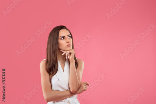 Pensive girl in blouse touching chin, looking at upper right corner and thinking, making choice. Copy space