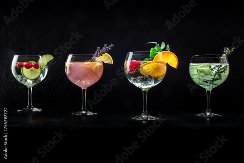 Fancy cocktails with fresh fruit, herbs, and flowers. Gin and tonic drinks with ice at a party, a variety, on a black background