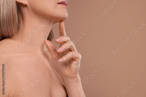 Woman touching her chin on beige background, closeup. Space for text