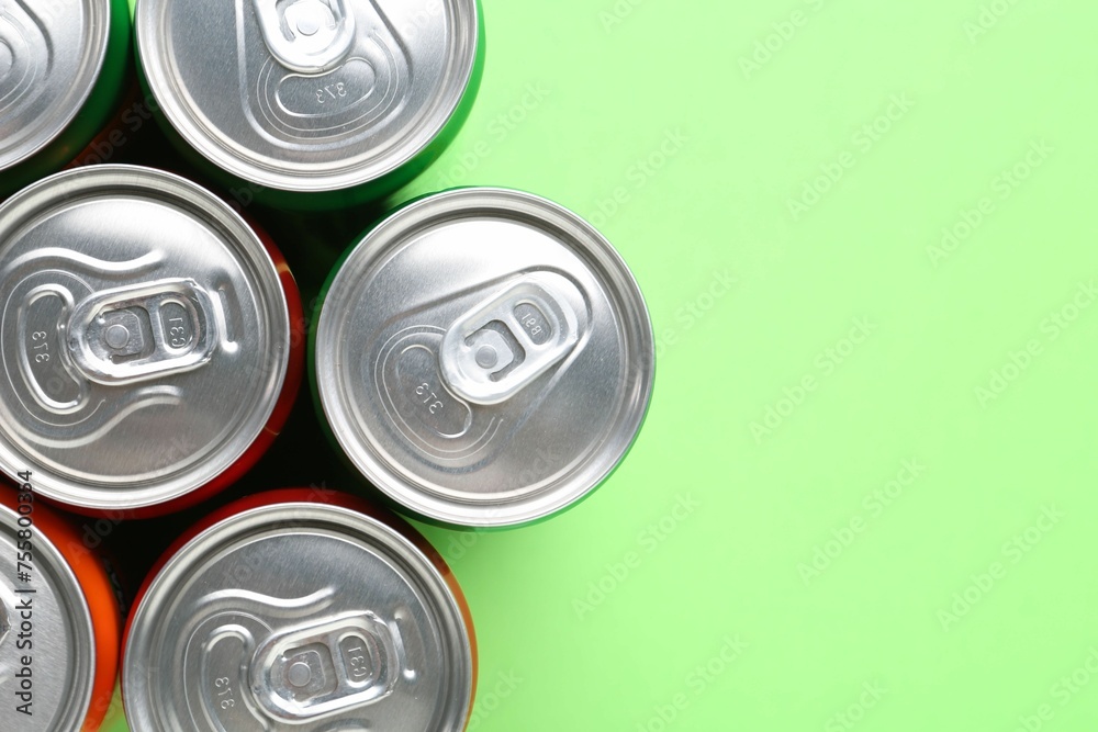Energy drink in cans on light green background, top view. Space for text Energy drink in cans on light green background, top view. Space for text