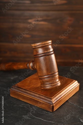 Wooden gavel and sound block on dark textured table, closeup