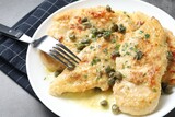 Delicious chicken piccata with herbs served on grey table, closeup