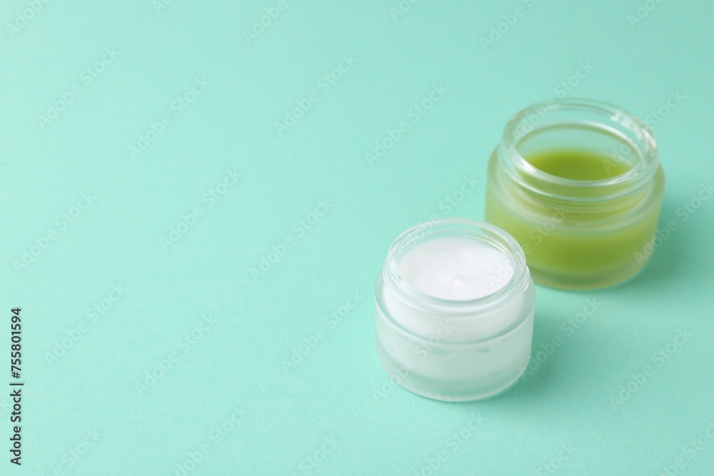 Moisturizing cream in open jars on turquoise background, space for text. Body care product Moisturizing cream in open jars on turquoise background, space for text. Body care product