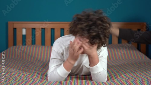 child violence - 9 year old boy in detention at home in bed being beaten by parent - crying in childhood and domestic abuse of children threatens to be hit with the belt as punishment
