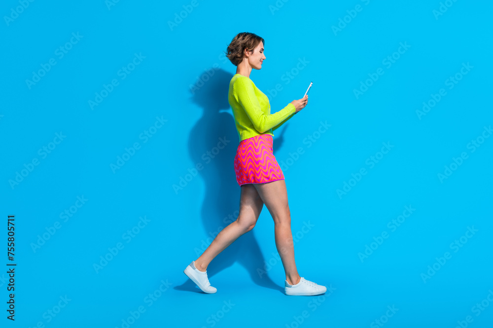 Full length body photo of young lady glamour outfit strolling holding mobile phone satisfied isolated on aquamarine color background Full length body photo of young lady glamour outfit strolling holding mobile phone satisfied isolated on aquamarine color background