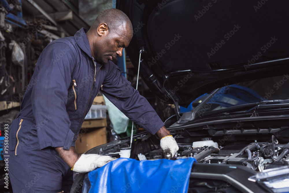 Black car mechanic man working in auto repair garage doing car maintenance and fixing work Black car mechanic man working in auto repair garage doing car maintenance and fixing work