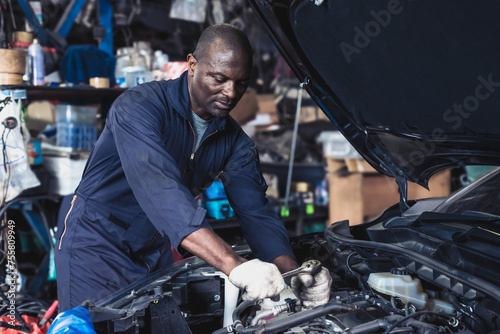 Fotografía Black car mechanic man fixing and changing vehicle engine in repair shop