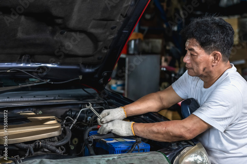 Expertise Asian auto mechanic man doing car repair and maintenance in auto garage