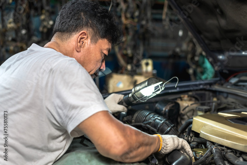 Expertise Asian auto mechanic man doing car repair and maintenance in auto garage