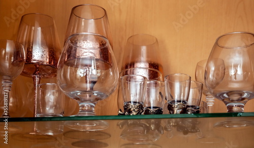 Purchased (consumer) glass glasses and glasses on the glass shelf of the kitchen cabinet close-up