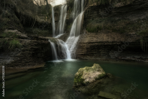 Detail of the Peñaladros waterfall, in Cozuelos, Valle de Angulo, Burgos, with a semi-submerged rock in the foreground photo