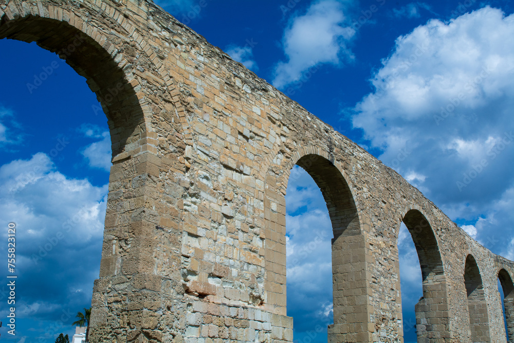 low-angle view of an ancient aqueduct against a blue sky