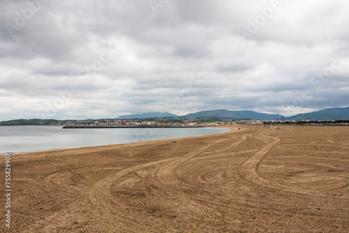 Beach of  town of Hondarribia in cloudy spring day with cars traces. Spain.