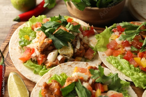 Delicious tacos with vegetables, meat and lime on table, closeup