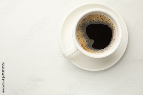 Cup of aromatic coffee on white table, top view. Space for text