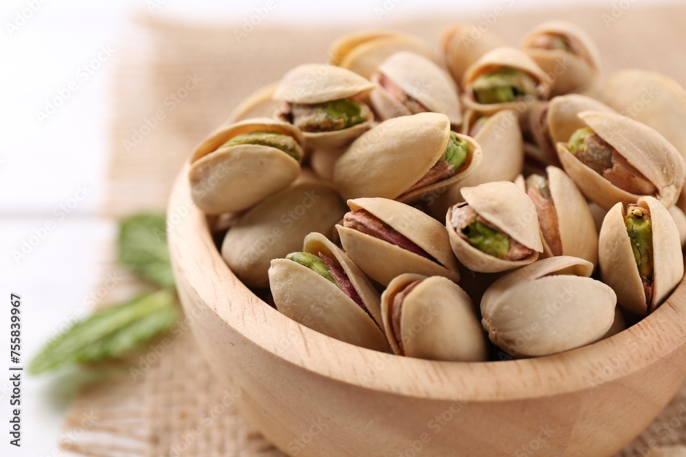 Tasty pistachios in bowl on white table, closeup Tasty pistachios in bowl on white table, closeup