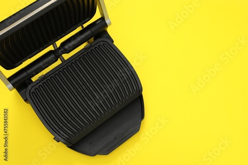 Electric grill on yellow background, top view. Space for text. Cooking appliance