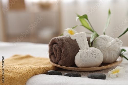 Spa stones, flowers and herbal bags on towel indoors, closeup