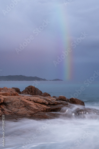 Long exposure of the Sardinian sea with silky waves and rainbow