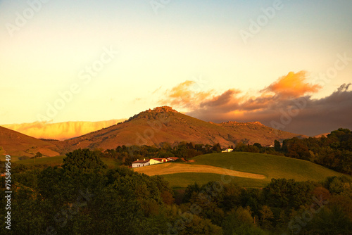 French Basque country landscape in beautiful golden sunset light. Traditional farm houses, fields and mountains. Rural spring holidays vacation in France.
