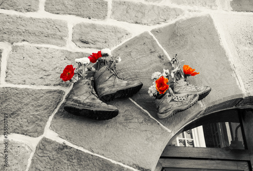 Old hiking shoes using as flower pot hanging stone wall house. Retro toned black white red vintage background. Lifestyle, natural leaving, travel, sustainable consumption concepts
