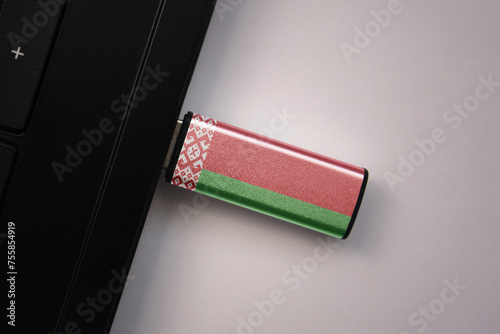 usb flash drive in notebook computer with the national flag of belarus on gray background.