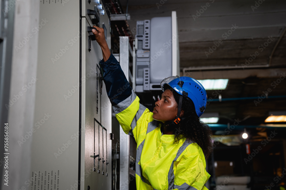 Technician in a yellow and blue safety vest is working on a panel Technician in a yellow and blue safety vest is working on a panel