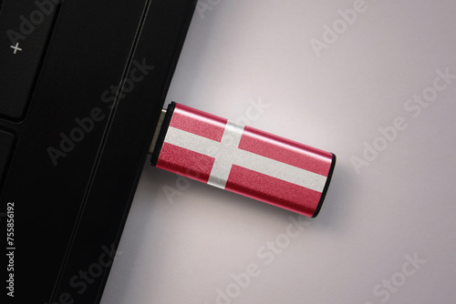 usb flash drive in notebook computer with the national flag of denmark on gray background.