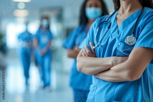 A group of nurses in blue scrubs stand in a hallway