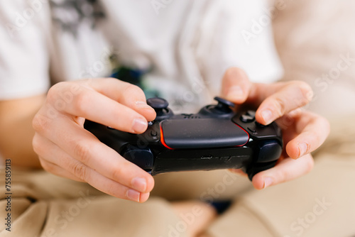 Close-up of a young gamer s hands operating a PS controller. Home game console  modern technology  games  entertainment.