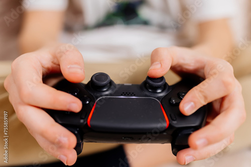 Close-up of a young gamer's hands operating a PS controller. Home game console, modern technology, games, entertainment.