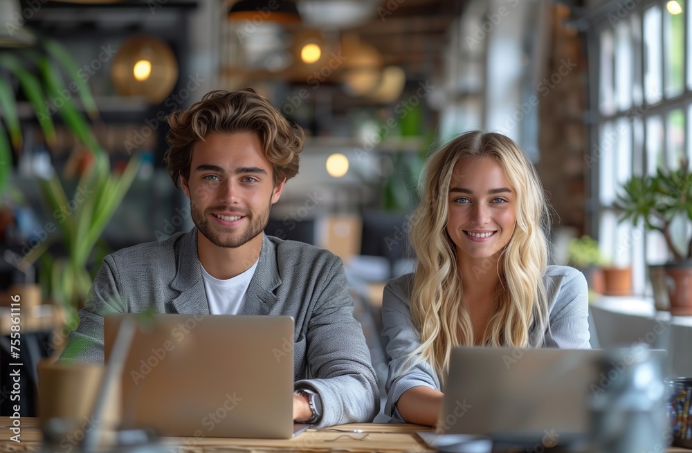 a man and a woman are sitting at a table with laptops a man and a woman are sitting at a table with laptops