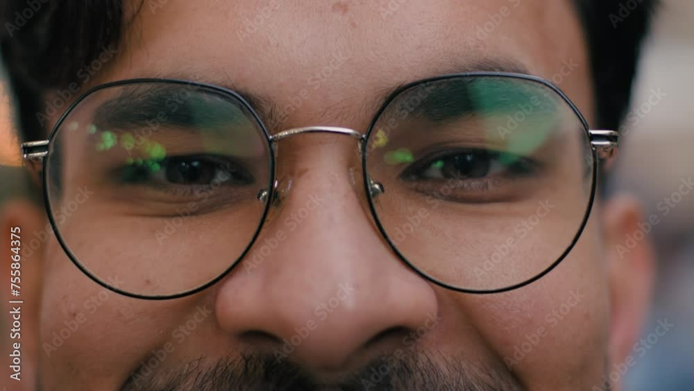 Close up happy Indian Arabian ethnic male student man guy businessman slowly opening brown eyes looking at camera eyewear glasses shake head smiling outdoors city urban street. Healthy vision eyesight Close up happy Indian Arabian ethnic male student man guy businessman slowly opening brown eyes looking at camera eyewear glasses shake head smiling outdoors city urban street. Healthy vision eyesight