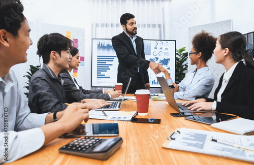 Diverse coworker celebrate with handshake and teamwork in corporate workplace. Happy business people united by handshaking after successful meeting or business presentation on data analysis. Concord