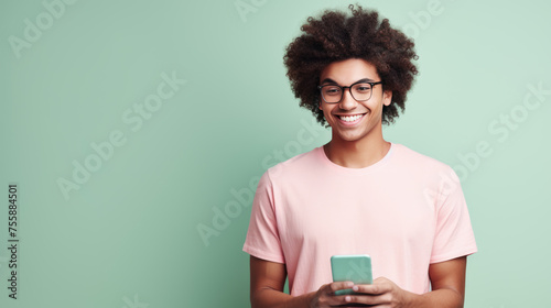 Young guy smiling holding a smartphone sitting against colored background
