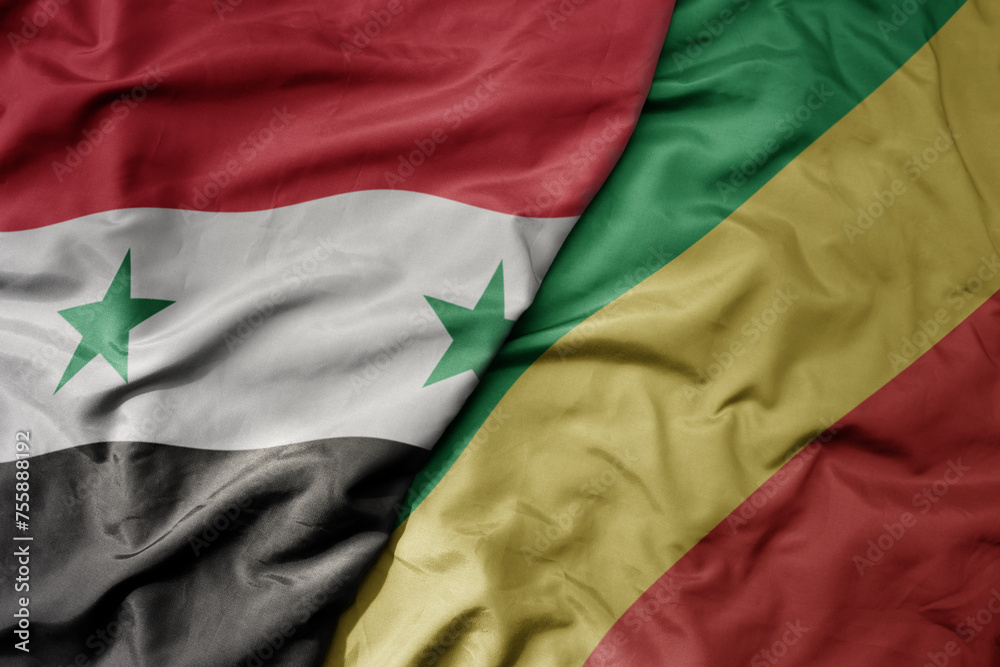 big waving national colorful flag of republic of the congo and national flag of syria .
