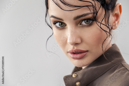 Beautiful young woman with stylish hairstyle posing at studio. Close-up face of a girl with bright fashionable make-up. Fashion model with beautiful eyes looks to the camera. Sexy girl.