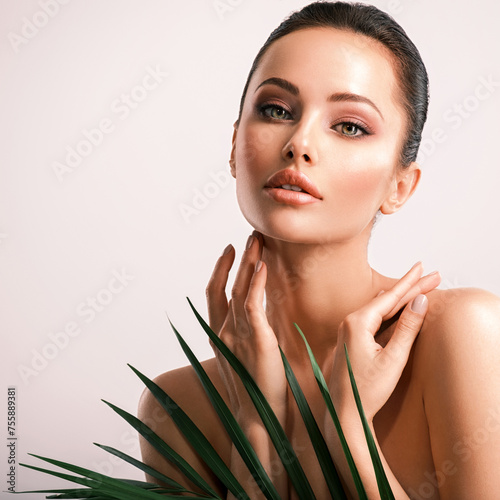 Young beautiful woman with green leaves near body. Skin care beauty treatments concept.  Closeup girl's face with green leaves.