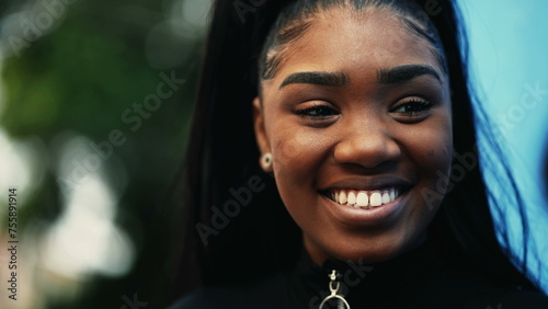 Close-up of a joyful black latina girl smiling and laughing. South American young woman in 20s happy expression while interacting with friends off-camera