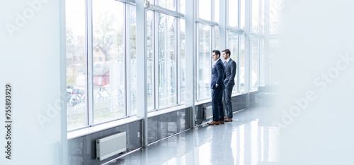 Full length portrait of Business team stand near the window in conference room.
