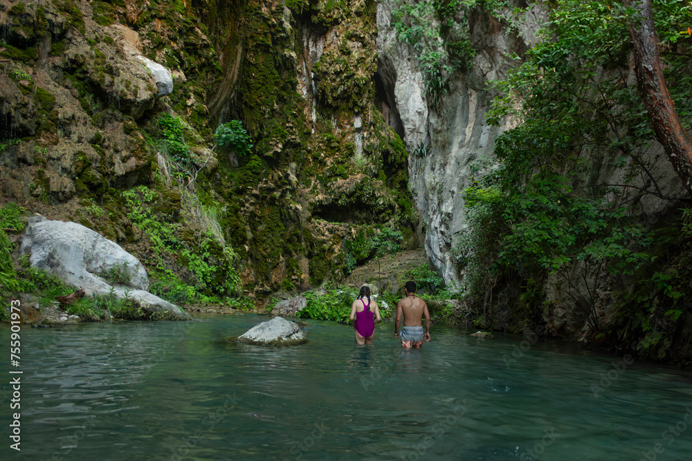 Man and woman heterosexual couple hiking healthy life style on ecotourism trip in Hidalgo, state of Mexico among the stalactites entering the grotto called La Gloria