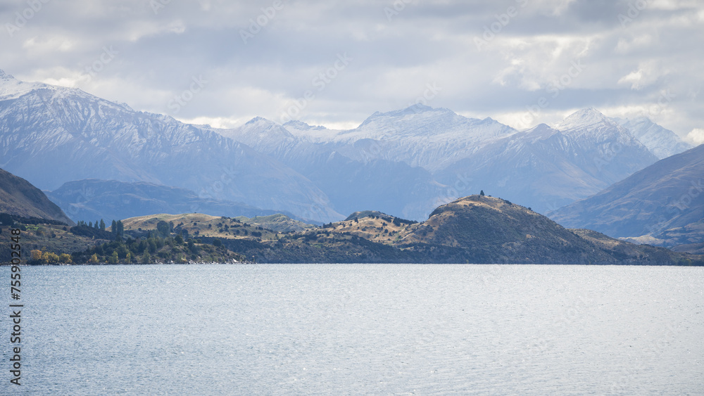 Landscape panorama with lake and hills and big snowy mountains in backdrop, New Zealand